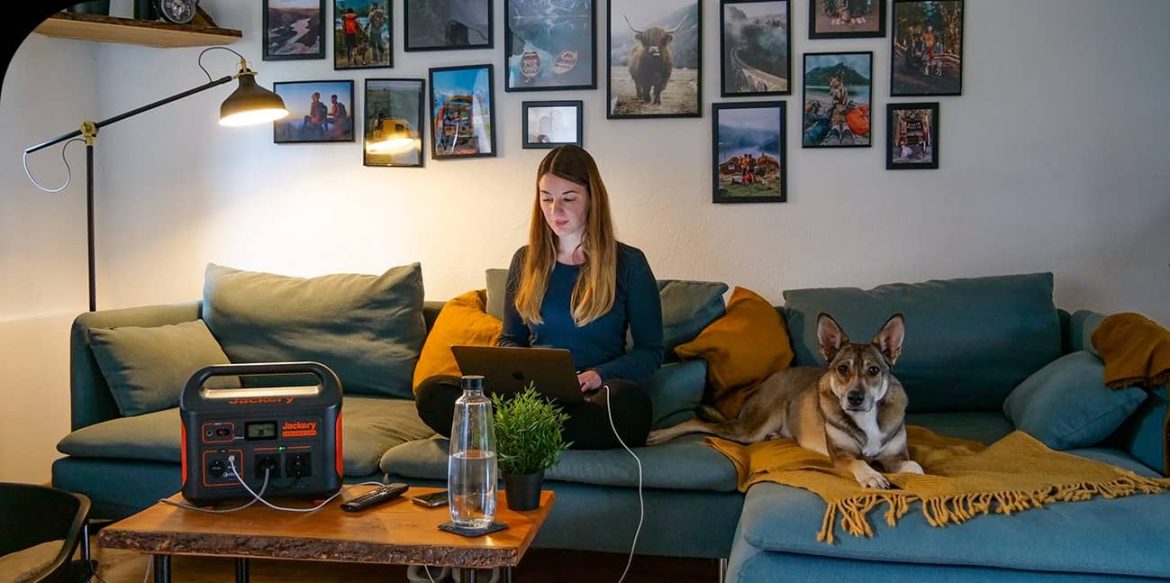 Femme travaillant sur un ordinateur portable alimenté par un petit générateur électrogène portable à la maison