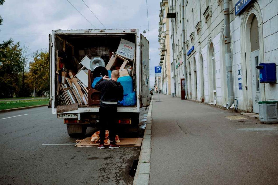 Un homme charge des cartons et des meubles en vrac dans un utilitaire pour savoir quelle taille de camion de déménagement pour un appartement 50m2 choisir.